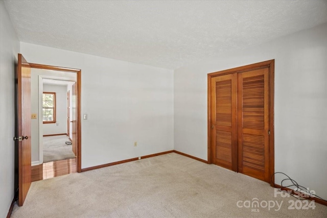 unfurnished bedroom featuring a closet, light carpet, and a textured ceiling