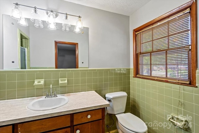 bathroom featuring toilet, a textured ceiling, vanity, and tile walls