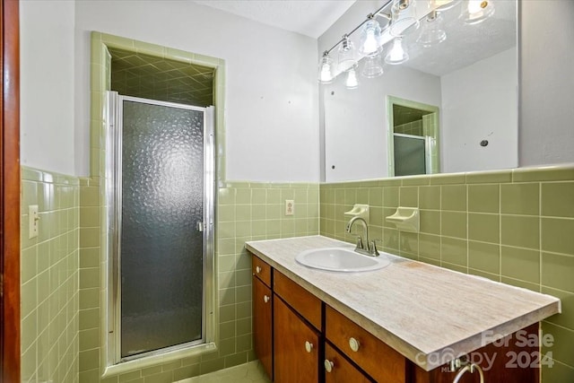 bathroom with a shower with door, vanity, and tile walls