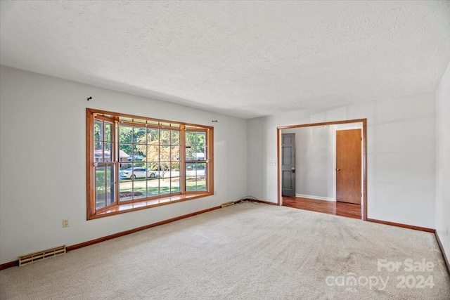 carpeted spare room featuring a textured ceiling