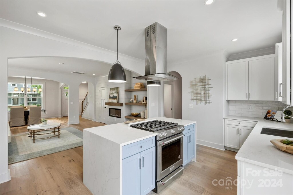 kitchen with island range hood, stainless steel range, and white cabinets