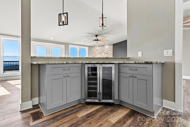 interior space featuring light stone countertops, beverage cooler, ceiling fan, decorative light fixtures, and gray cabinets