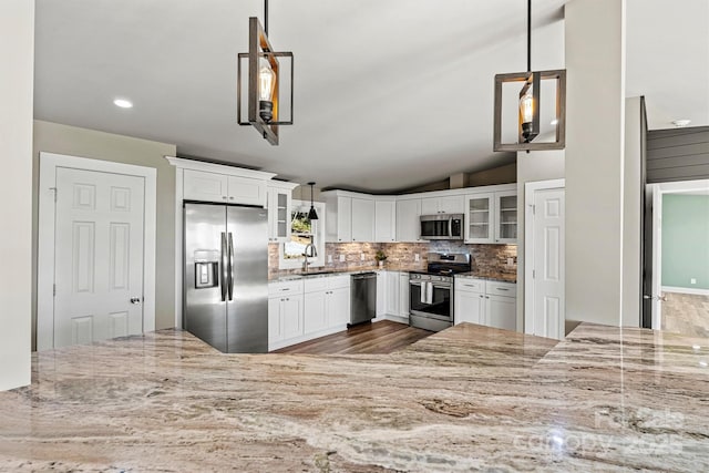 kitchen with stainless steel appliances, backsplash, vaulted ceiling, decorative light fixtures, and white cabinets