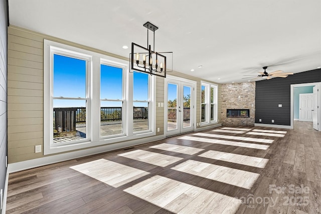 unfurnished living room featuring a healthy amount of sunlight, a stone fireplace, and wooden walls