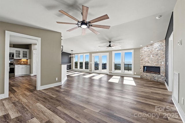 unfurnished living room with hardwood / wood-style floors, ceiling fan, a fireplace, and french doors