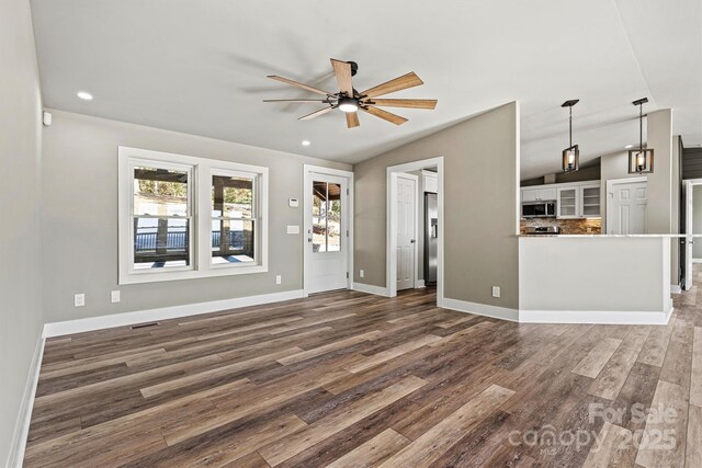 unfurnished living room with ceiling fan, dark hardwood / wood-style flooring, and vaulted ceiling