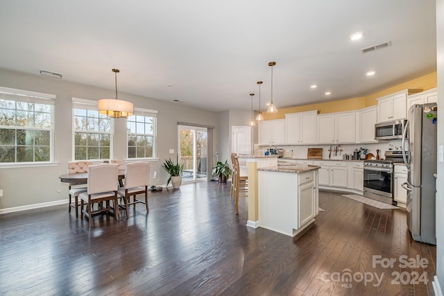 kitchen featuring stainless steel appliances, hanging light fixtures, dark wood-type flooring, and a kitchen island