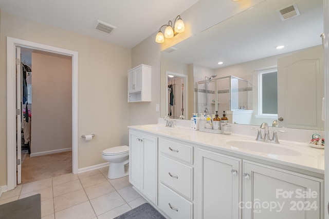 bathroom with toilet, vanity, tile patterned floors, and a shower with door