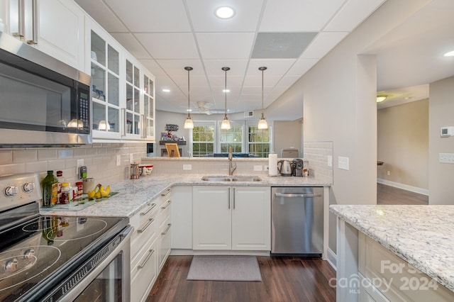 kitchen with stainless steel appliances, white cabinetry, backsplash, sink, and dark wood-type flooring