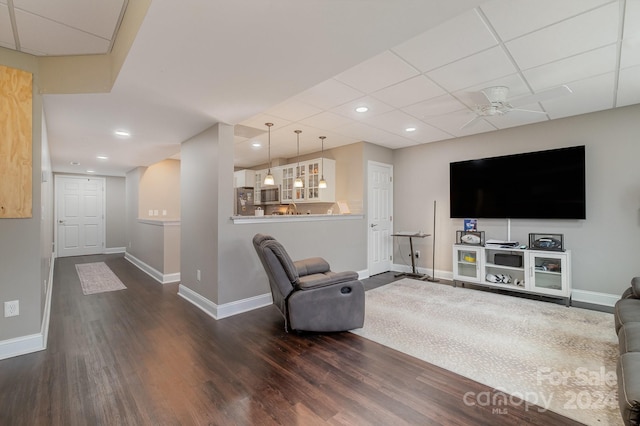 living room featuring a drop ceiling, hardwood / wood-style flooring, and ceiling fan