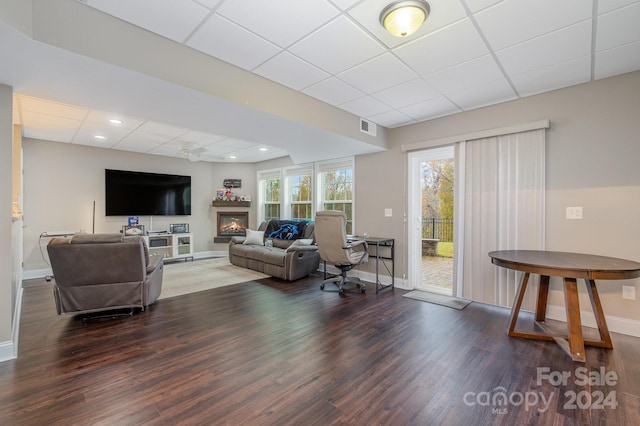 living room with dark hardwood / wood-style floors and a drop ceiling