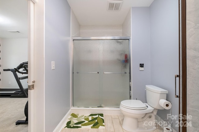 bathroom featuring toilet and a shower with door