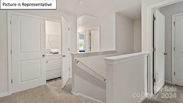 hallway with washer / dryer and light colored carpet