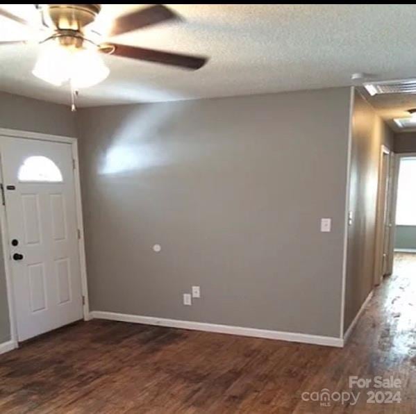 entryway with dark wood-type flooring, ceiling fan, and a textured ceiling