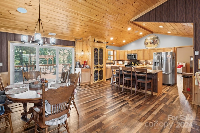 dining area with wooden walls, vaulted ceiling, a notable chandelier, and dark hardwood / wood-style flooring