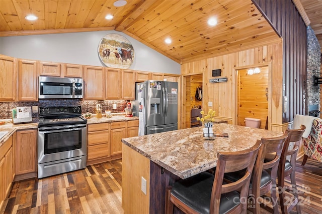 kitchen featuring dark hardwood / wood-style floors, light stone countertops, stainless steel appliances, and a kitchen island