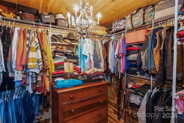 walk in closet featuring hardwood / wood-style flooring and an inviting chandelier