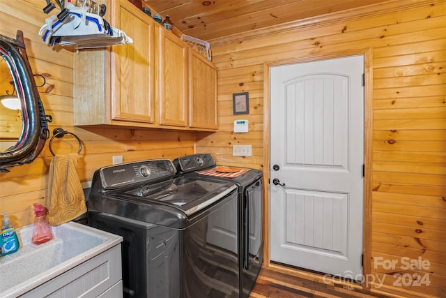 clothes washing area featuring wooden walls, washer and clothes dryer, wooden ceiling, and cabinets