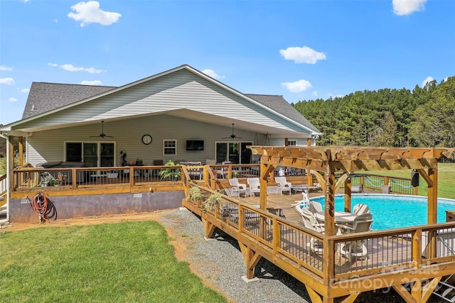 rear view of house with ceiling fan, a yard, a swimming pool side deck, and a pergola