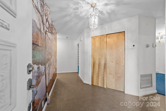 hallway with a notable chandelier and dark parquet flooring