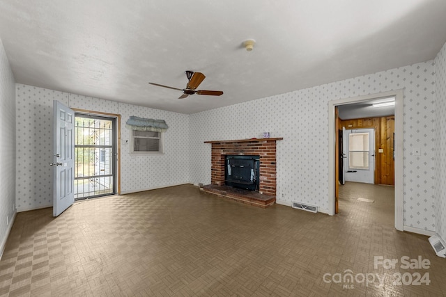 unfurnished living room featuring a wood stove and ceiling fan