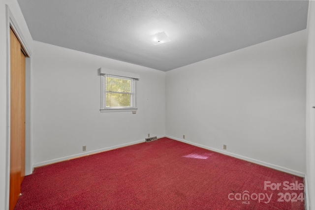 unfurnished bedroom featuring a textured ceiling, carpet flooring, and a closet