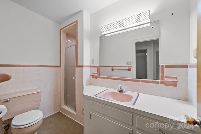 bathroom featuring toilet, a shower with shower door, vanity, and tile walls