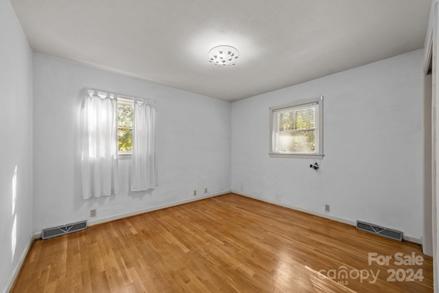 empty room with hardwood / wood-style flooring and plenty of natural light