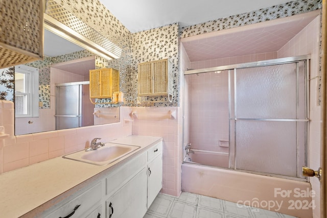 bathroom with vanity, enclosed tub / shower combo, and tile walls