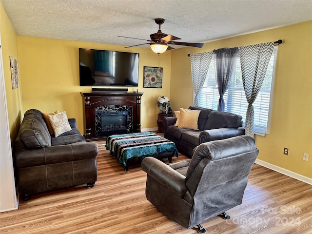 living room featuring ceiling fan, a textured ceiling, and light hardwood / wood-style flooring