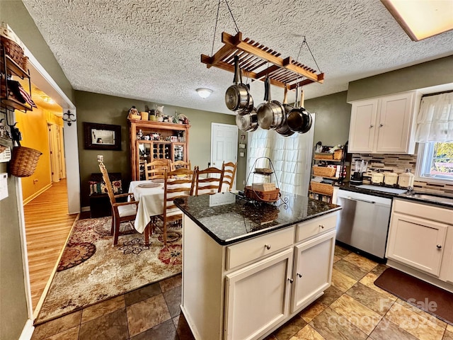 kitchen featuring stainless steel dishwasher, a kitchen island, white cabinetry, and light hardwood / wood-style flooring