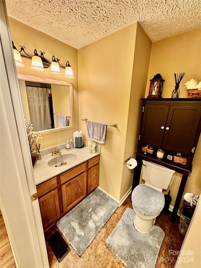 bathroom with vanity, a textured ceiling, toilet, and tile patterned floors