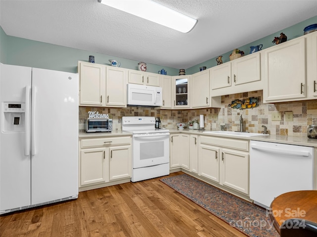 kitchen with sink, light hardwood / wood-style floors, white appliances, and white cabinets