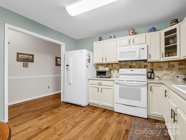 kitchen featuring white appliances, tasteful backsplash, white cabinetry, and light hardwood / wood-style flooring