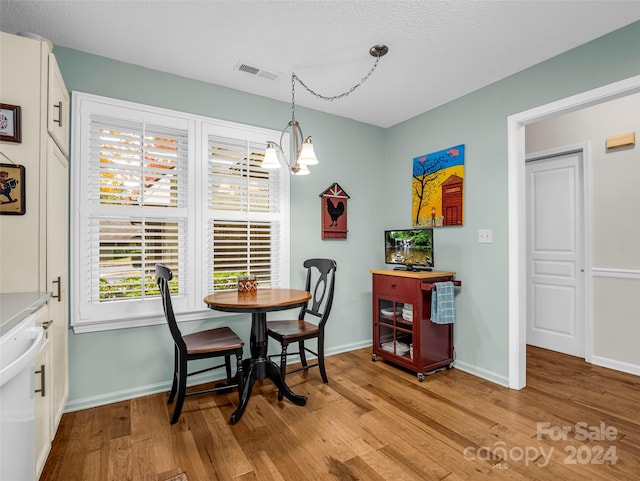 dining room featuring an inviting chandelier, light hardwood / wood-style flooring, and a textured ceiling