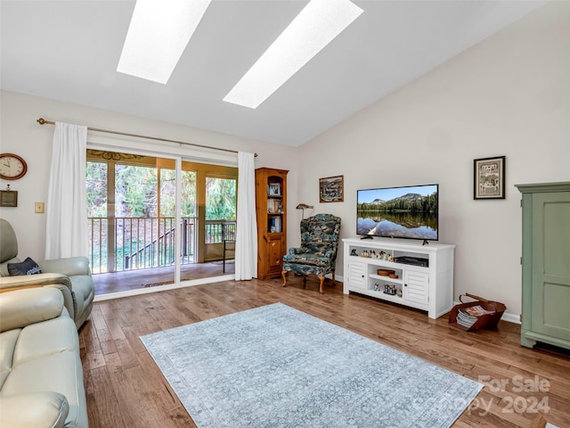 living room featuring hardwood / wood-style floors, high vaulted ceiling, and a skylight