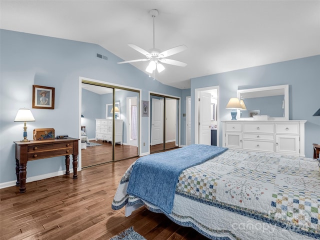 bedroom with ensuite bath, hardwood / wood-style floors, vaulted ceiling, two closets, and ceiling fan