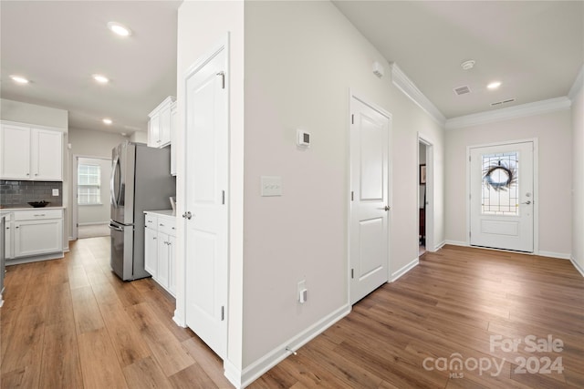 entryway with crown molding and light hardwood / wood-style floors