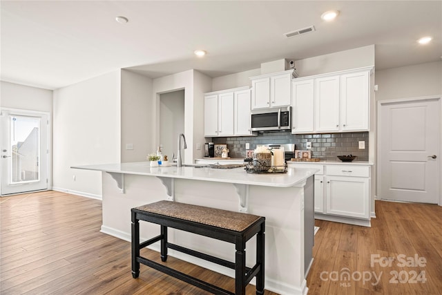 kitchen featuring white cabinetry, light hardwood / wood-style flooring, and a kitchen island with sink