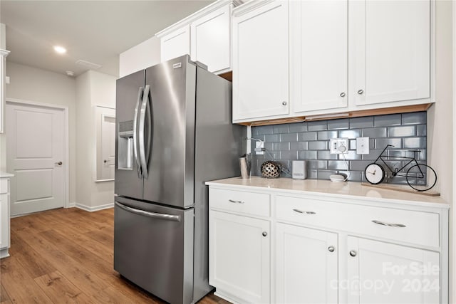 kitchen featuring light hardwood / wood-style floors, stainless steel refrigerator with ice dispenser, white cabinets, and tasteful backsplash