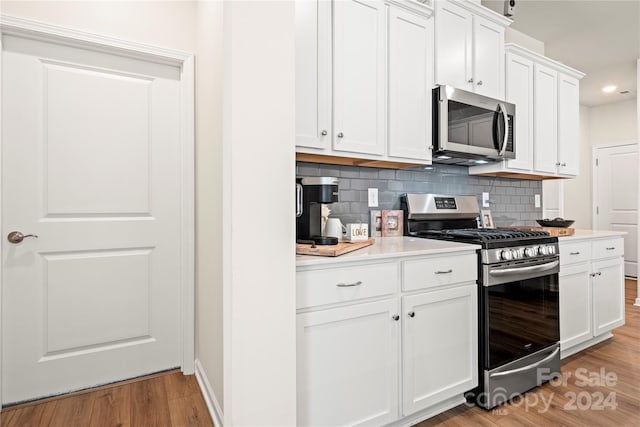 kitchen with decorative backsplash, light hardwood / wood-style flooring, white cabinetry, and stainless steel appliances