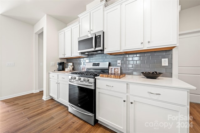 kitchen with light hardwood / wood-style floors, appliances with stainless steel finishes, backsplash, and white cabinets