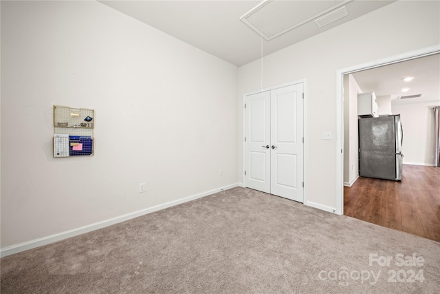 unfurnished bedroom featuring hardwood / wood-style floors and stainless steel refrigerator