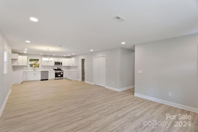 unfurnished living room with a chandelier, sink, and light wood-type flooring