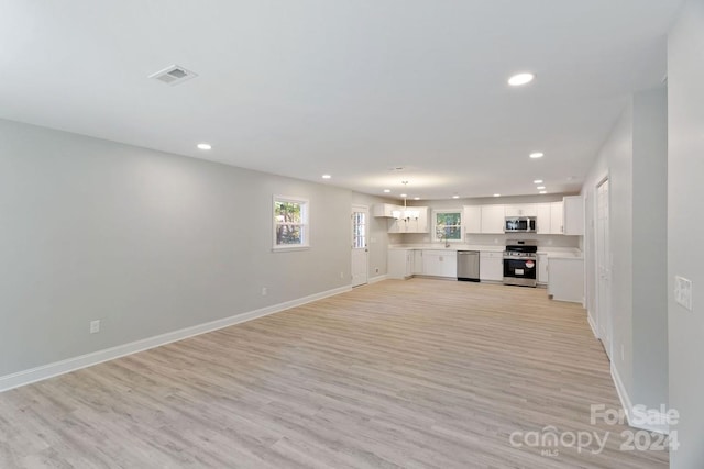 unfurnished living room featuring a chandelier, sink, and light wood-type flooring