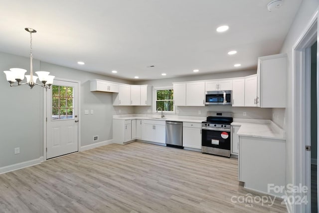 kitchen featuring appliances with stainless steel finishes, white cabinets, light wood-type flooring, and a wealth of natural light