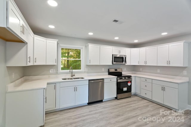 545 Shamel Ct, Winston Salem, NC 27105 - kitchen with appliances with stainless steel finishes, a sink, white cabinets, recessed lighting, and light wood-style flooring