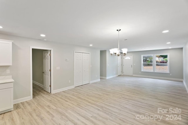 unfurnished living room featuring light hardwood / wood-style floors and a notable chandelier