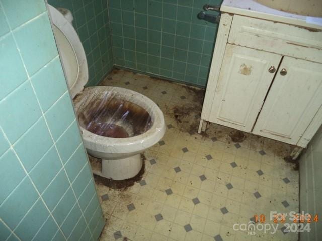 bathroom featuring toilet and tile walls