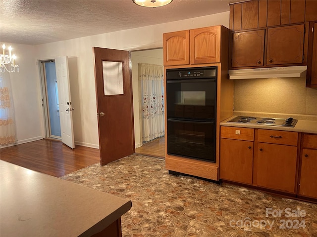 kitchen featuring white gas stovetop, a textured ceiling, a chandelier, dark hardwood / wood-style floors, and double oven